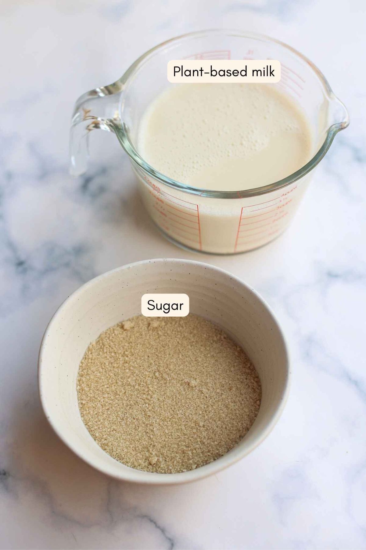Jug of milk and bowl of sugar on a marble benchtop.