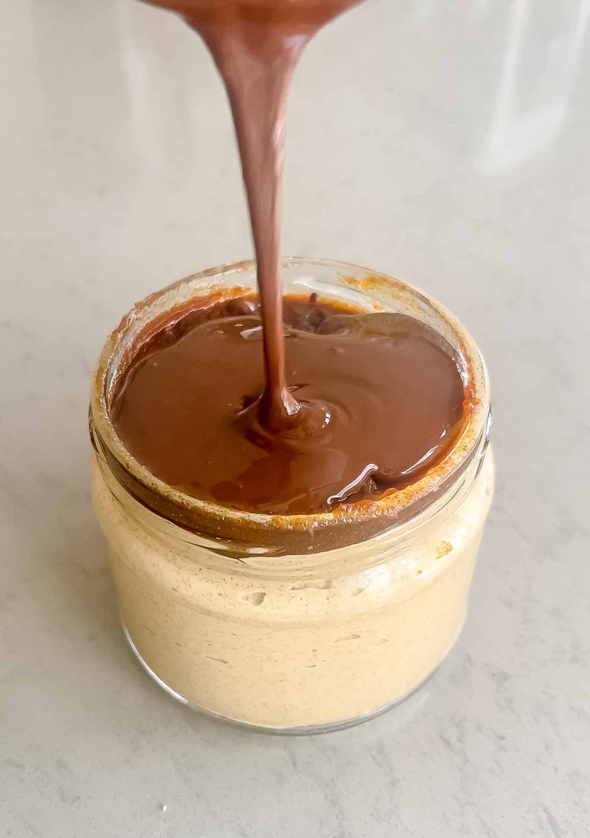 Jar of oats with melted chocolate poured on top.