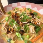 Spoon dipping into noodle soup bowl.