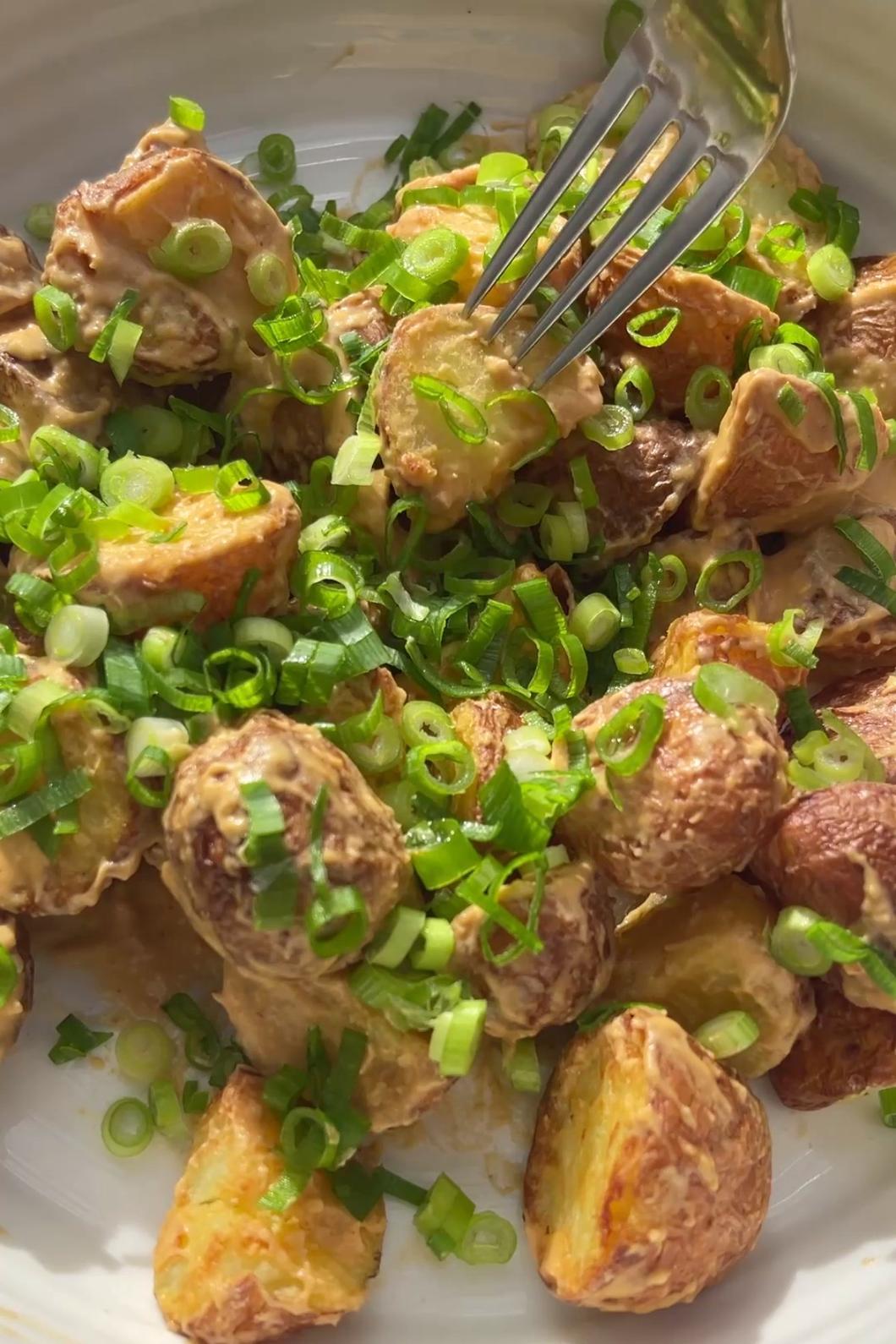 Golden roasted potatoes tossed with creamy dressing and topped with chopped green onions.
