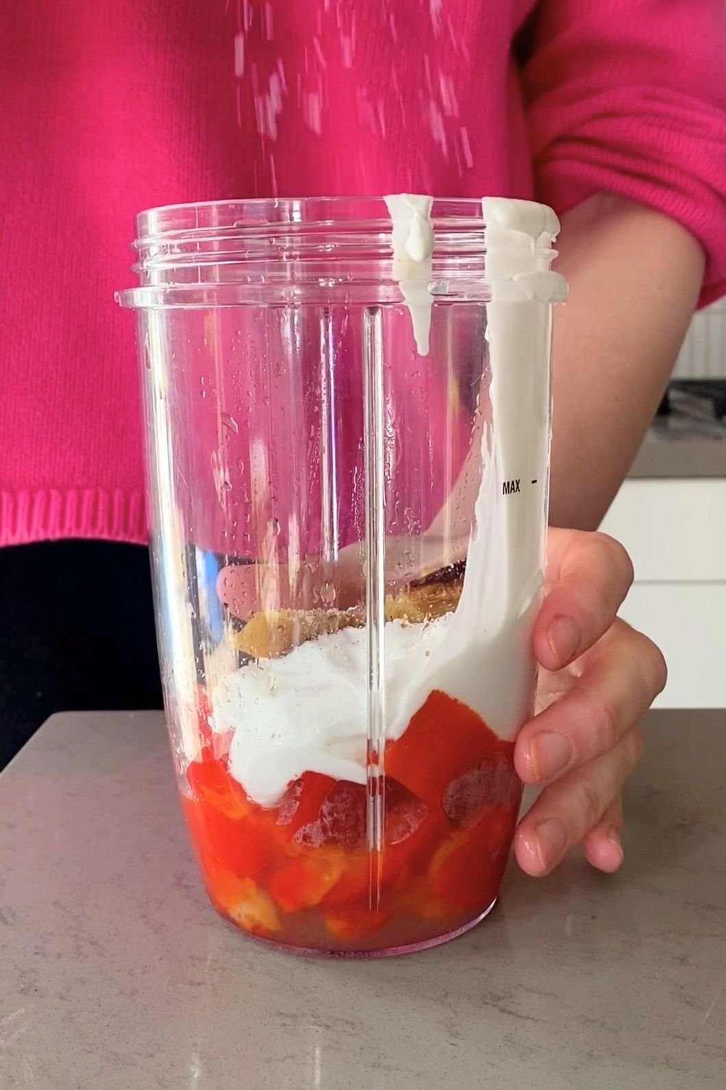 A woman (Liz Douglas) adds ingredients into a blender cup.