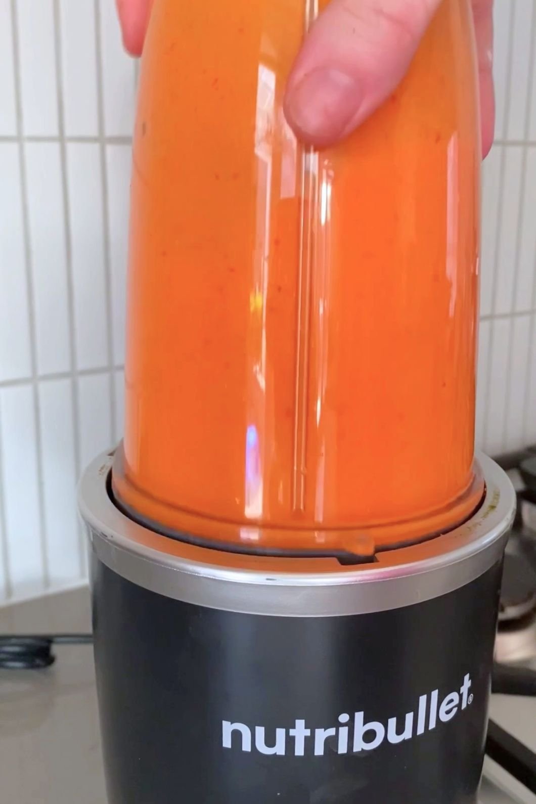 Bright orange sauce blending to a smooth consistency in a clear blender. 
