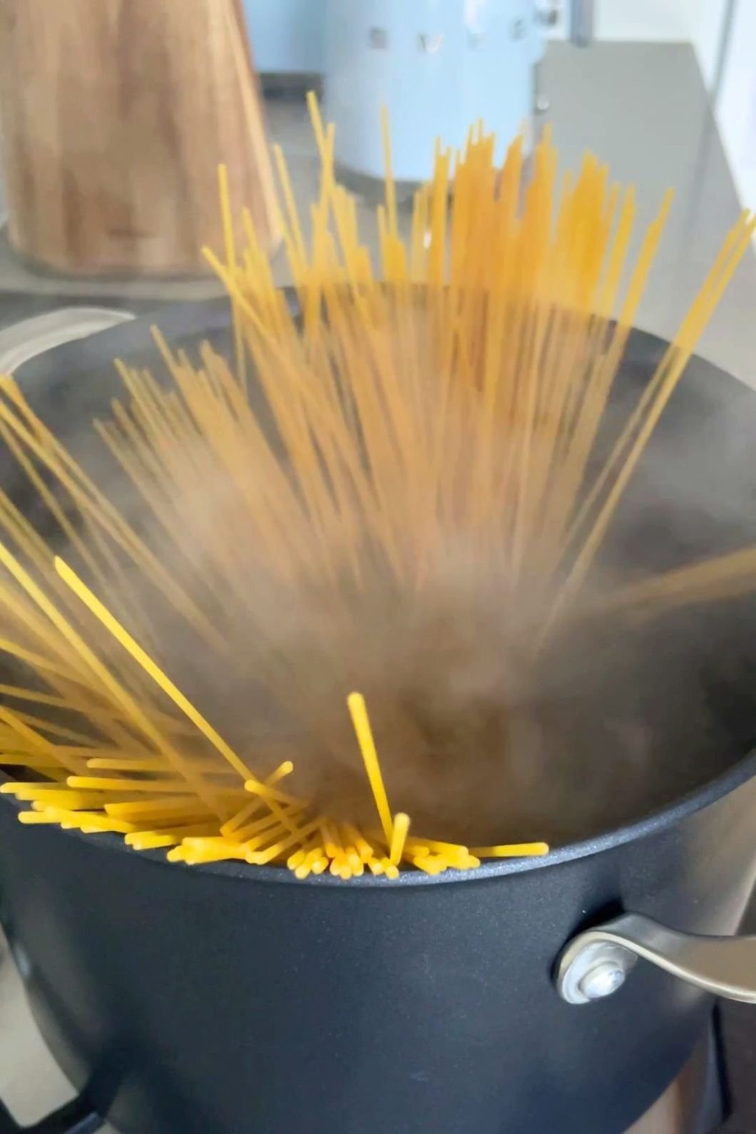 Dry spaghetti in a steaming pot of boiling water on the stove.