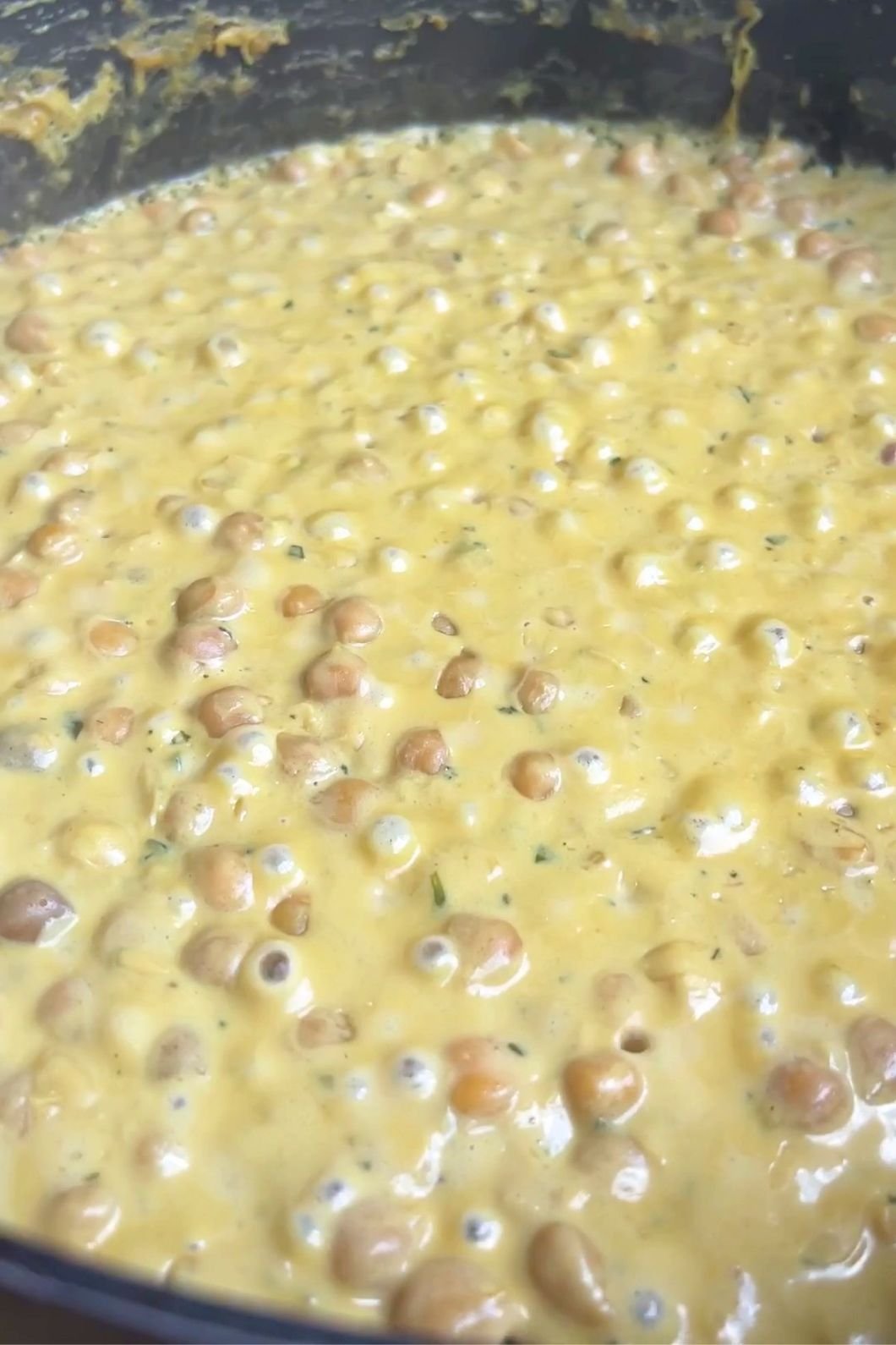 Creamy chickpea sauce simmering in a pan with small bubbles on the surface.