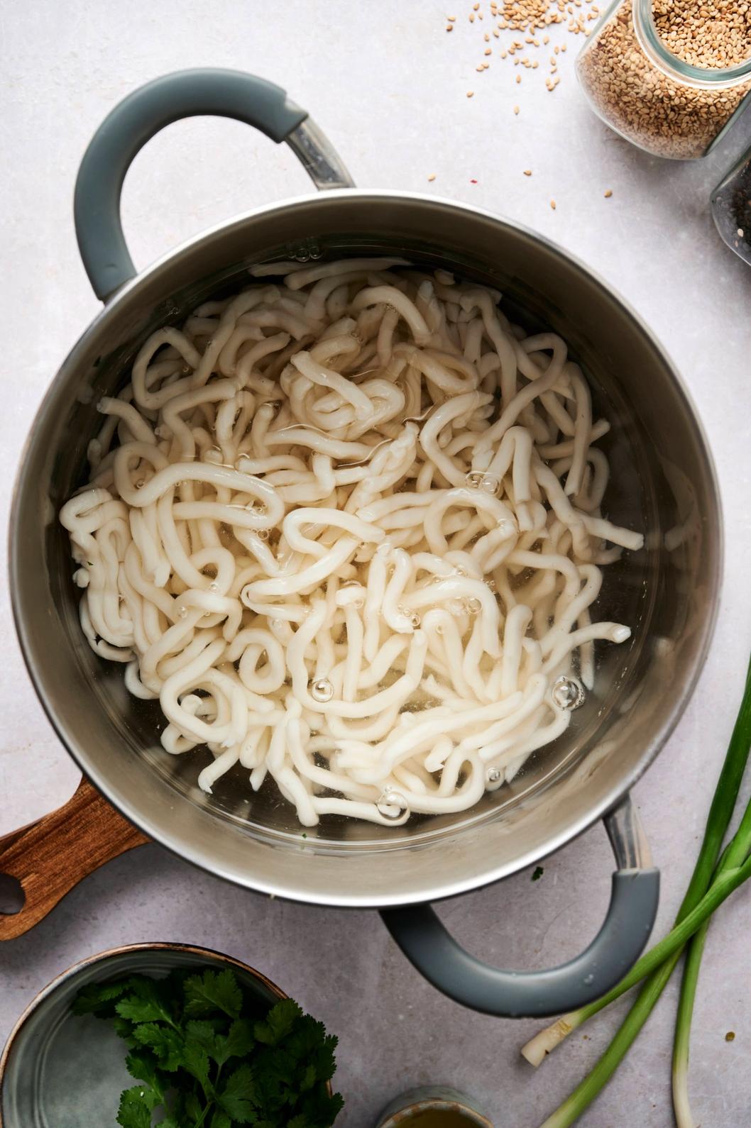 Pot of noodles simmering in water on the counter.