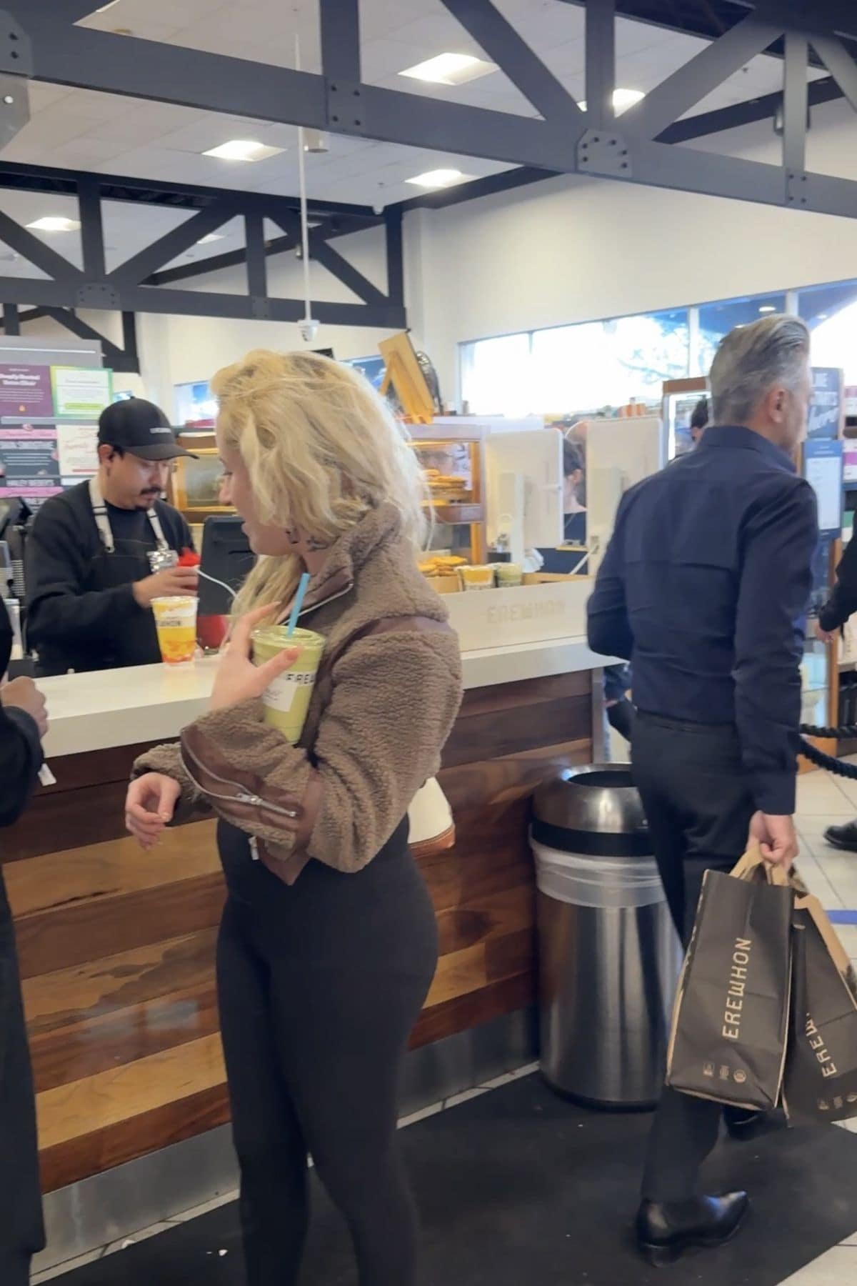 Customers waiting at the Erewhon smoothie bar while a staff member makes drinks.