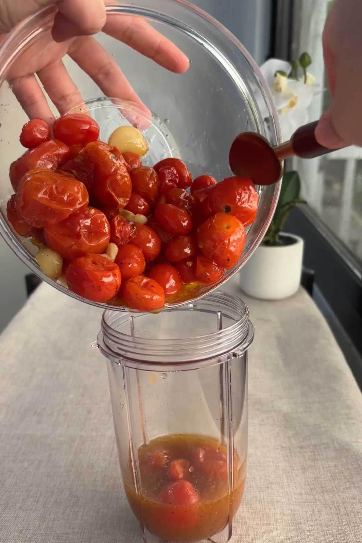 Roasted cherry tomatoes and garlic poured into a blender.