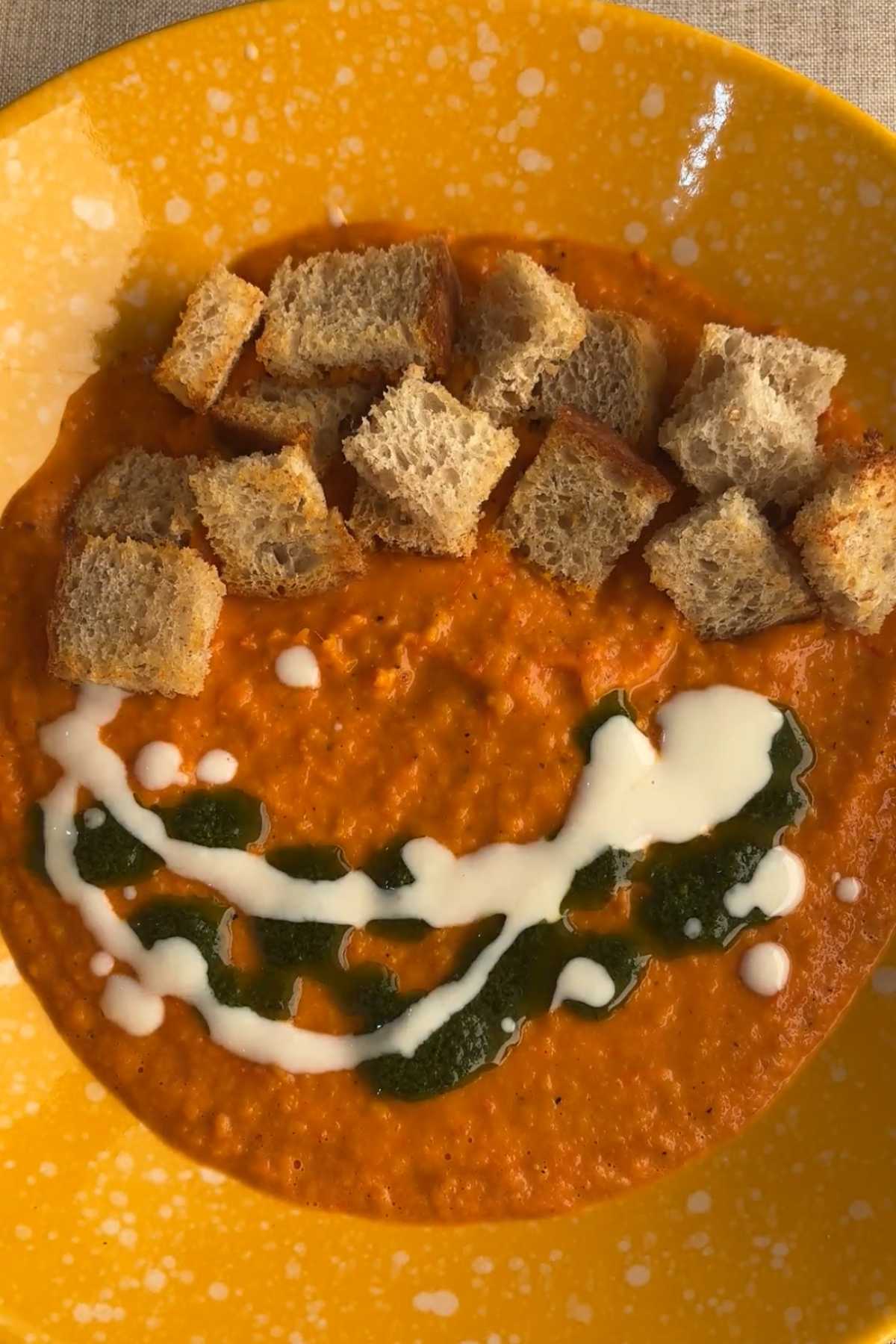 Tomato soup topped with croutons, yogurt, and basil oil.