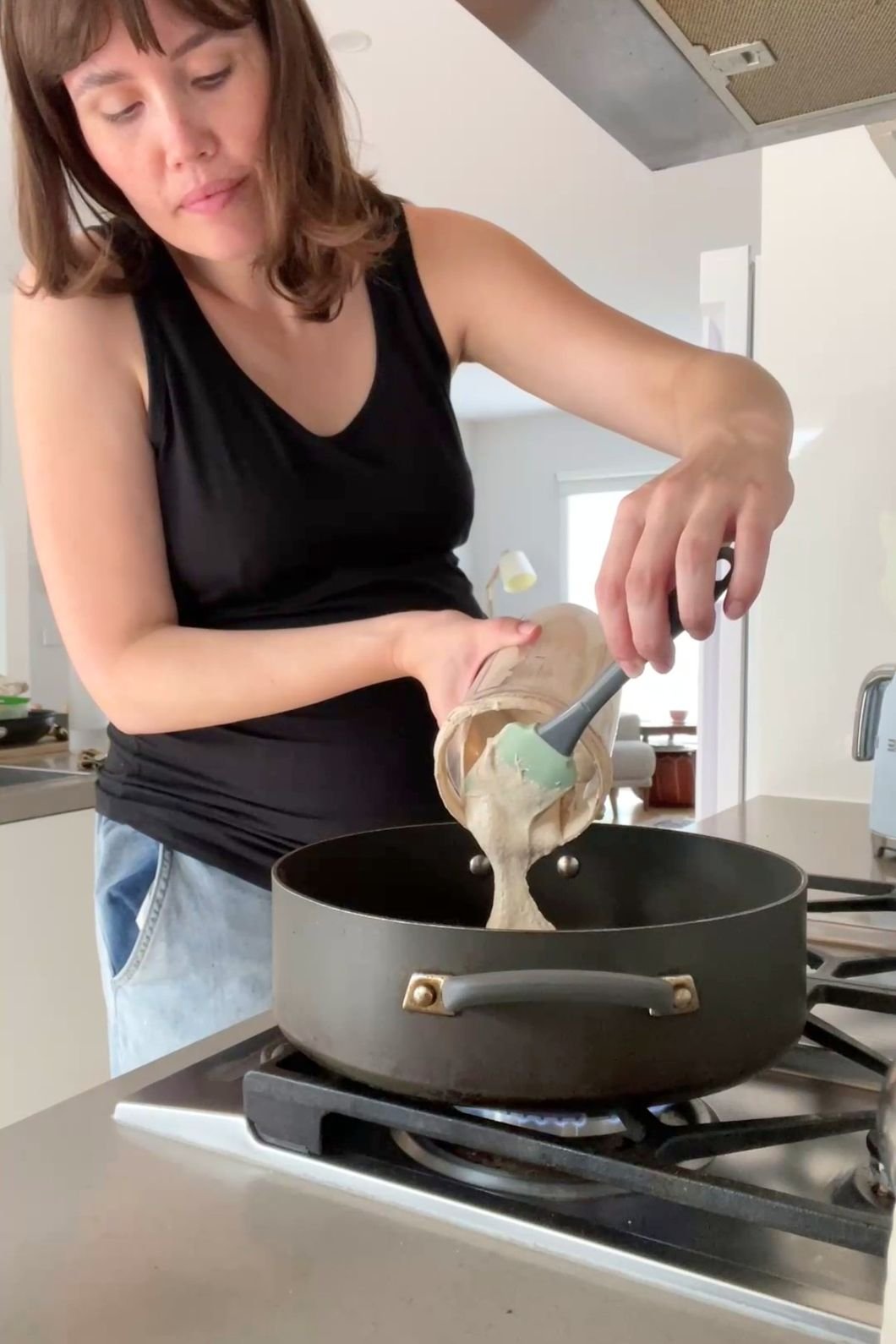 Woman (Liz Douglas) pours pancake batter into hot pan.