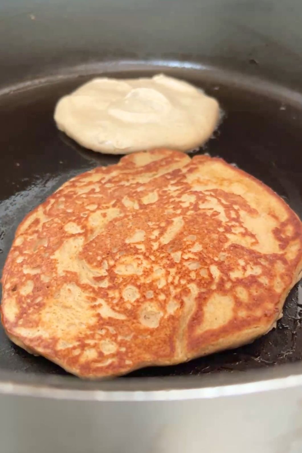Golden pancake cooking beside fresh batter.