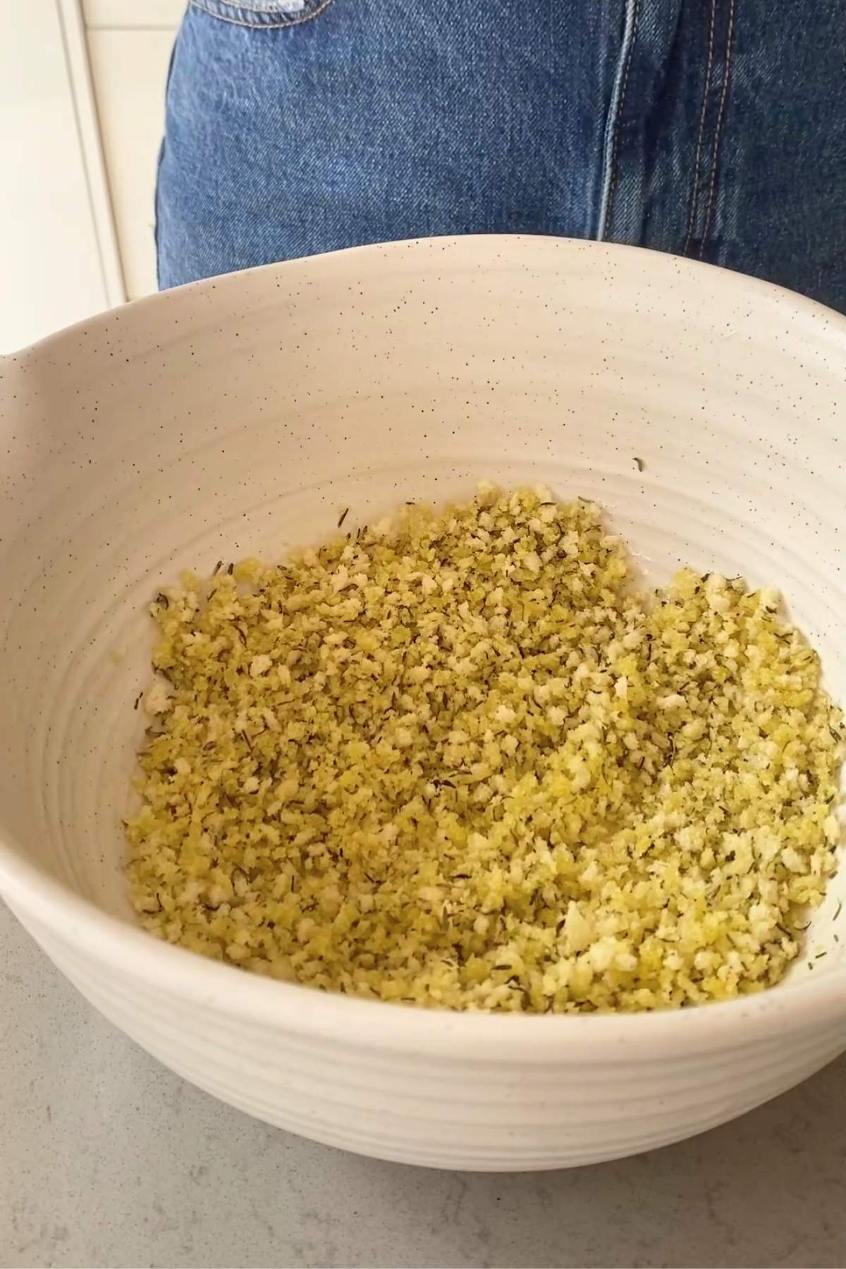 Seasoned panko breadcrumb topping with herbs and nutritional yeast in a large white speckled bowl.