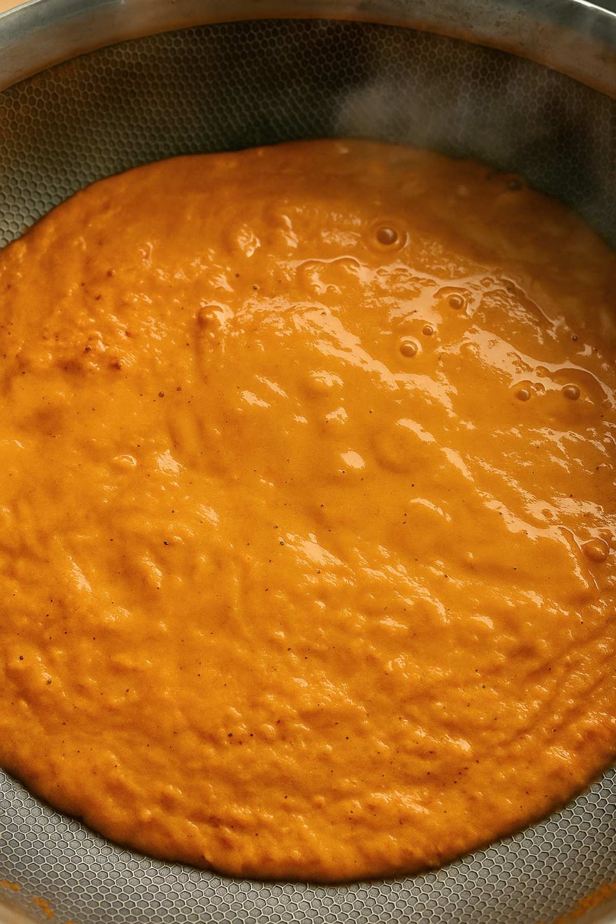 Blended tomato soup simmering in a saucepan.