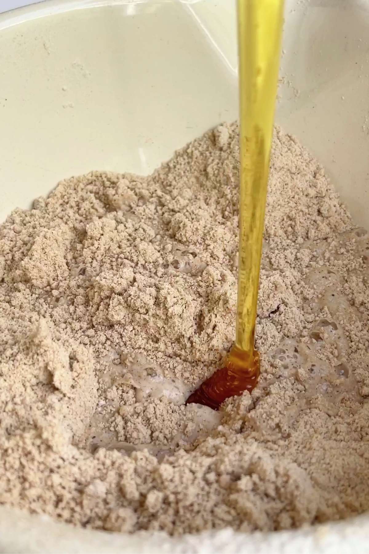 A stream of golden syrup pours into a bowl of spiced flour and bubbling liquid.