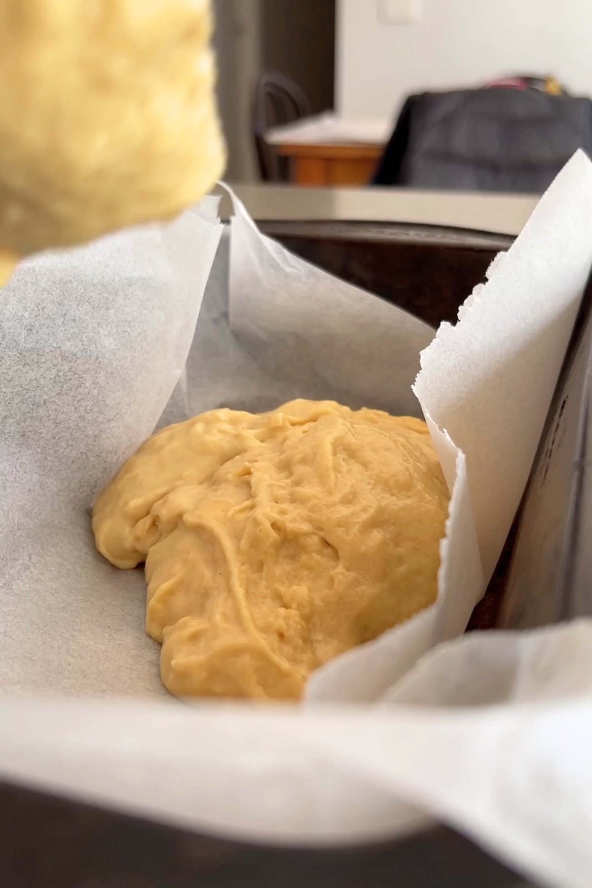 Soft vegan cheese mixture spread into a parchment-lined baking tin, ready to set.