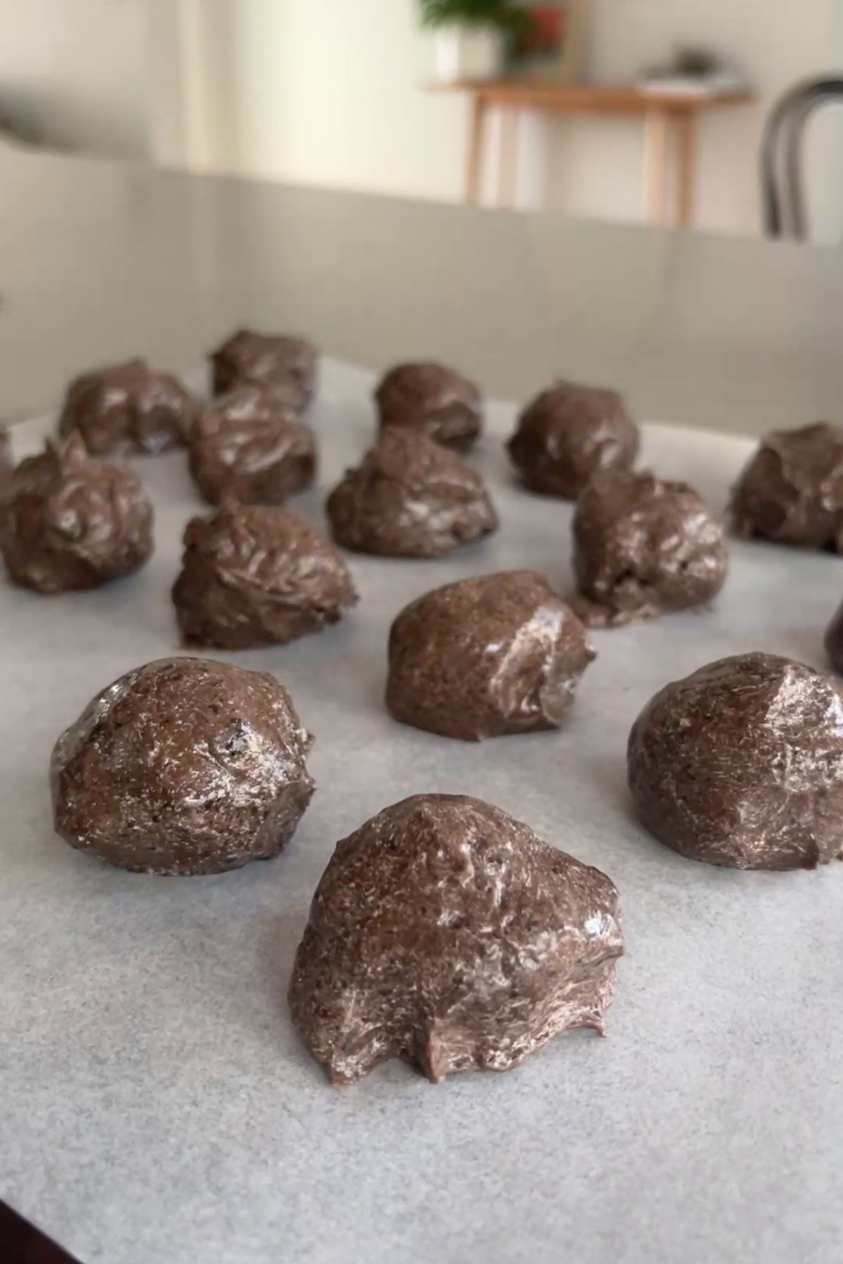 Roughly shaped Oreo truffle balls resting on a sheet of baking paper, ready to be chilled.