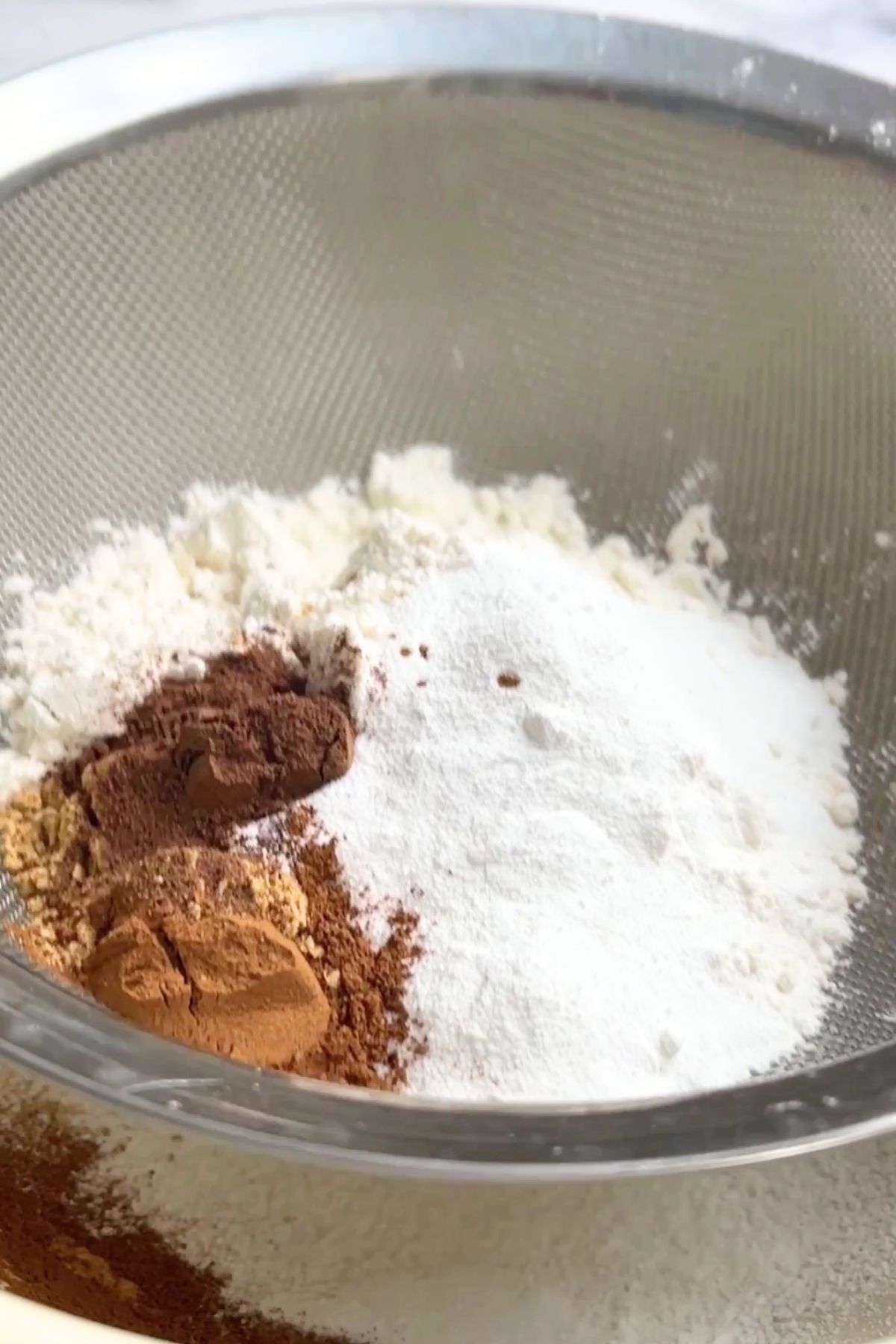 Dry ingredients sifted into a bowl, showing flour, baking powder, cinnamon, ginger, and allspice ready to be mixed for pancake batter.
