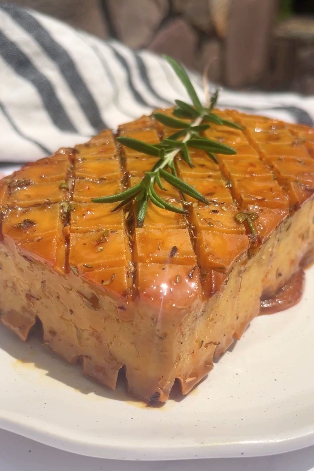 Golden glazed tofu block with a crosshatched top, glossy finish, and garnished with a sprig of fresh rosemary.