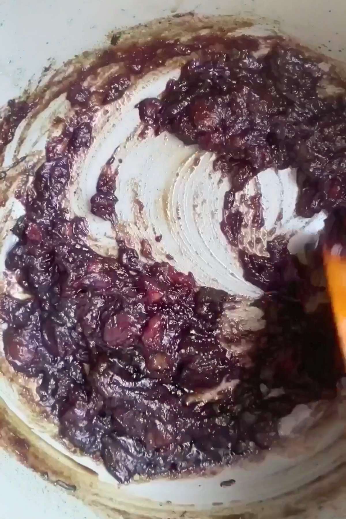 Dark brown date mixture being stirred in a saucepan with visible fruit bits.