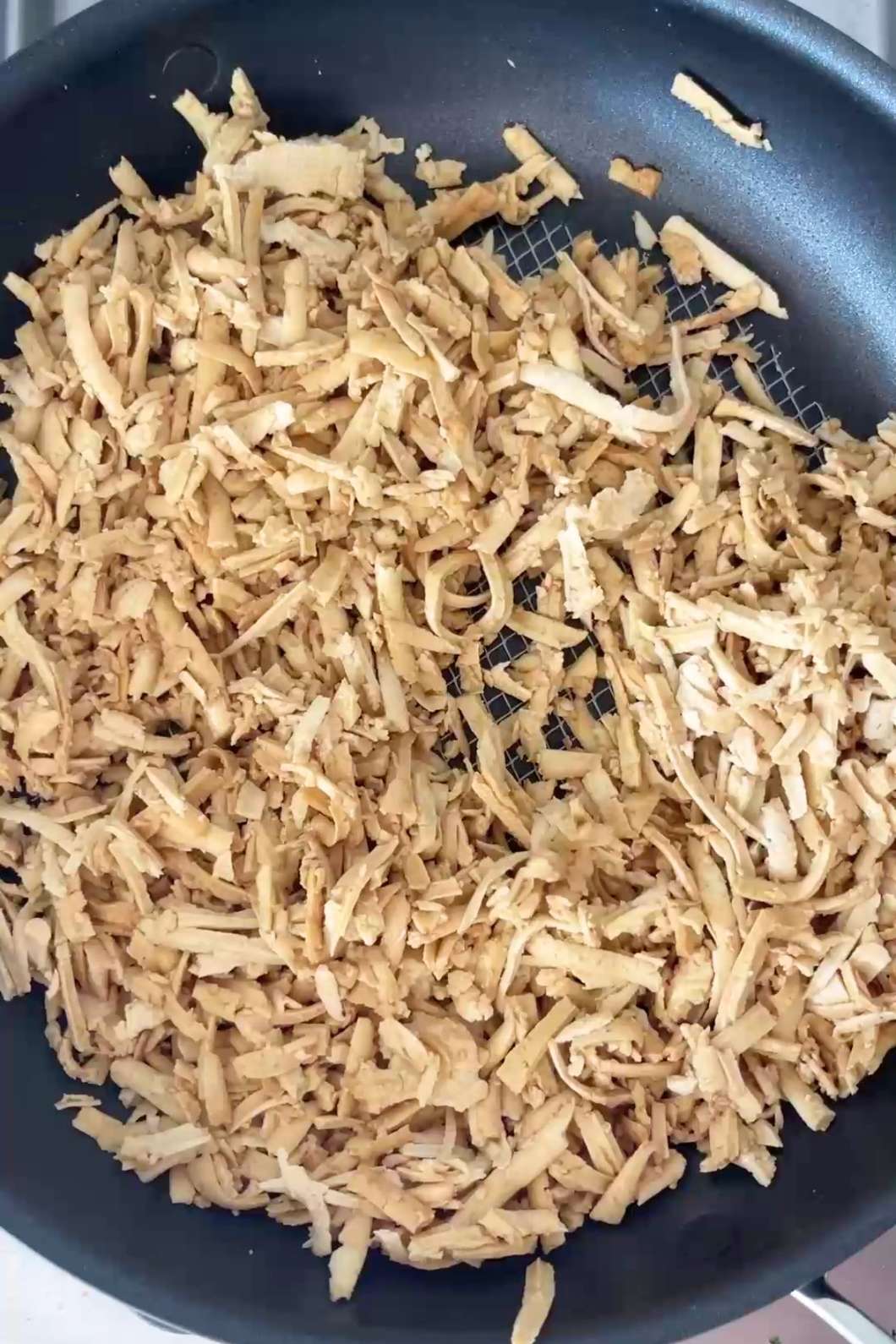 Shredded tofu cooking in skillet.