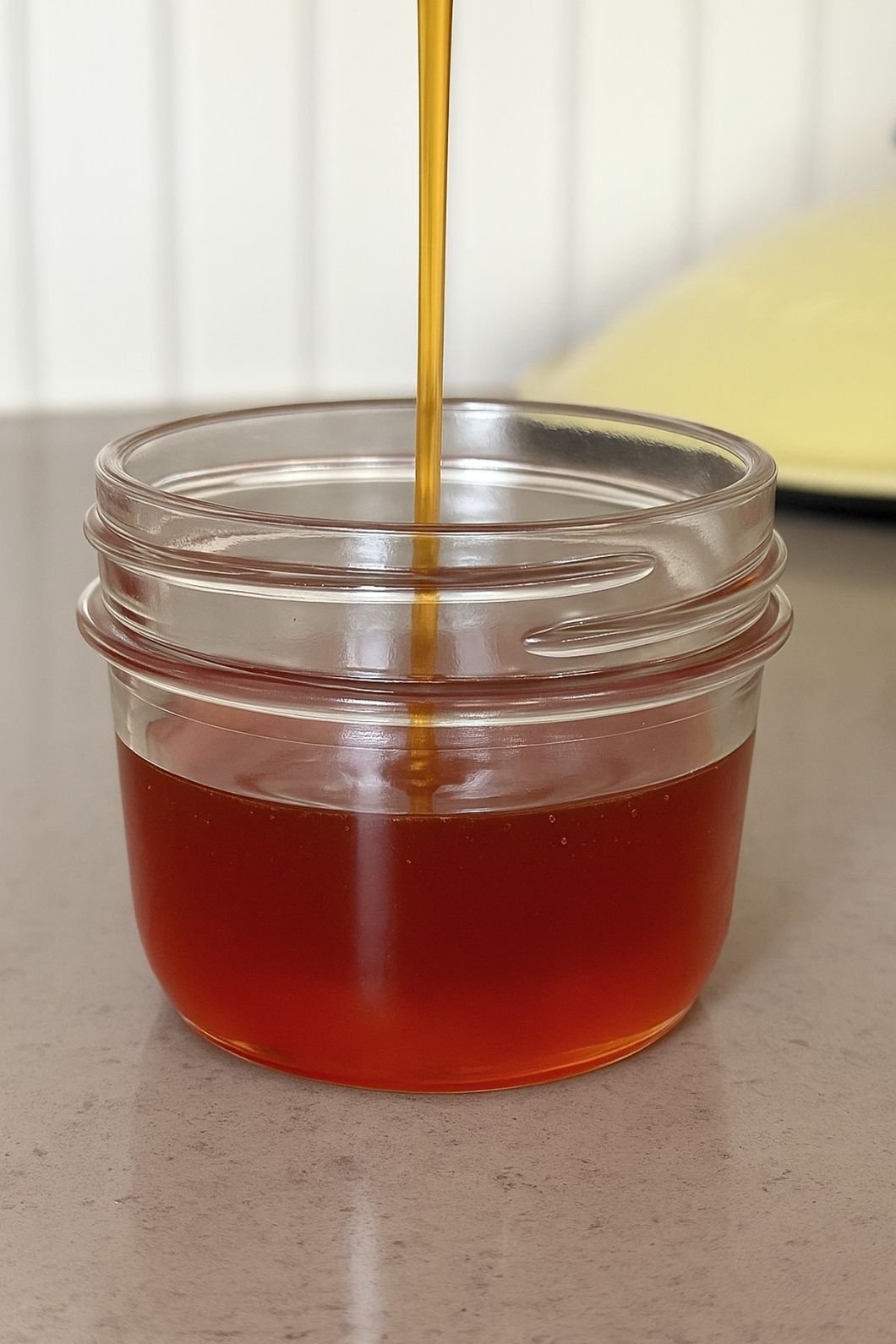 Vegan honey drizzling into glass jar.