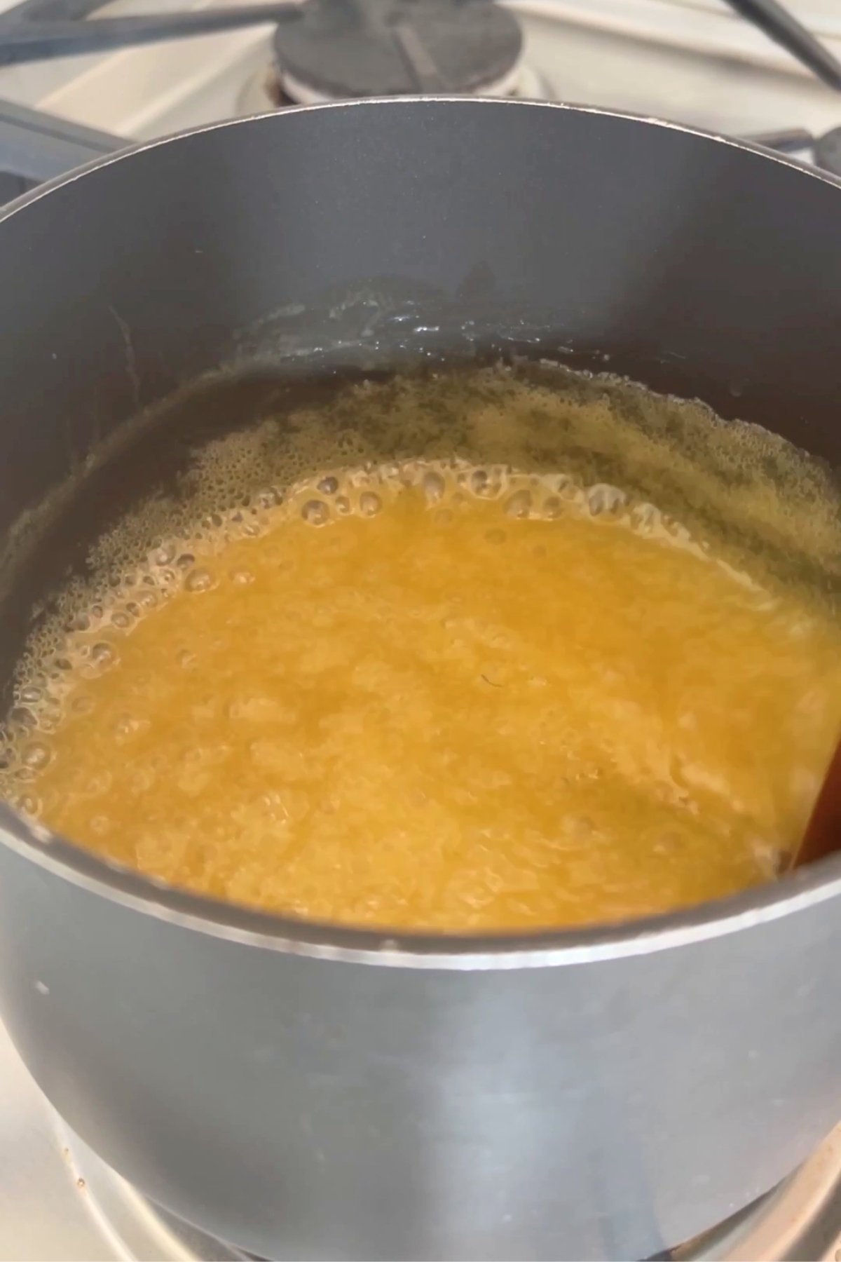 Golden mixture bubbling gently in a saucepan as it simmers and thickens over low heat.