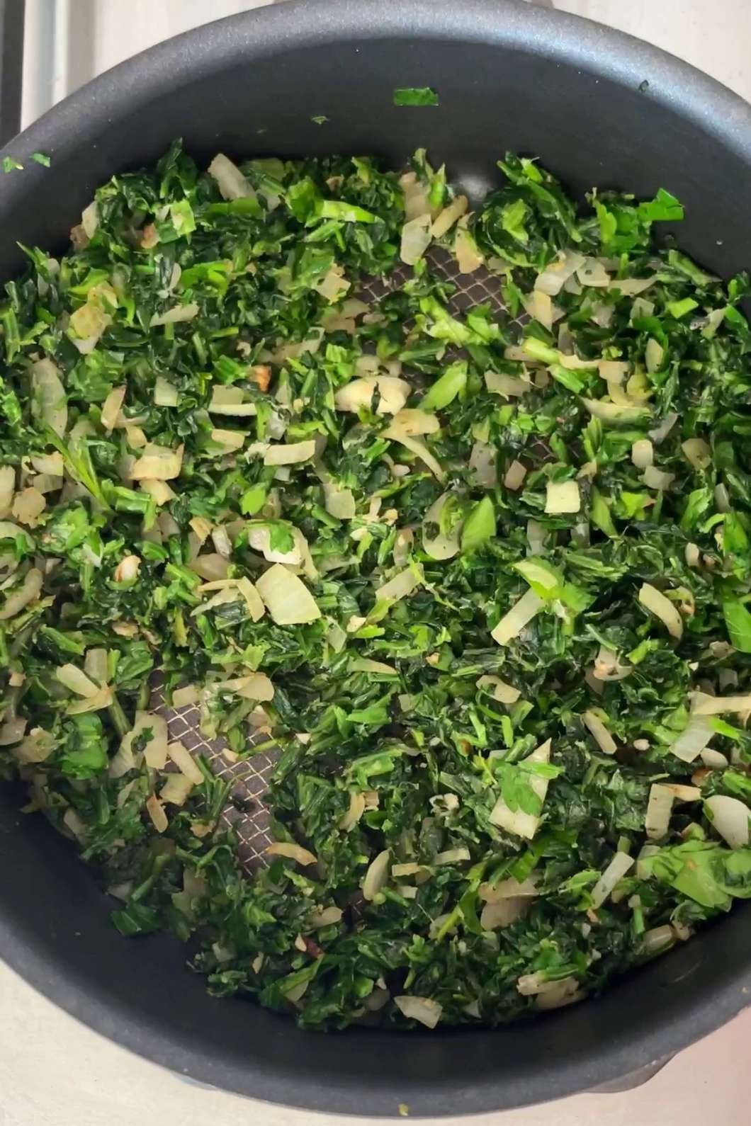 Sautéed spinach and onions in pan.