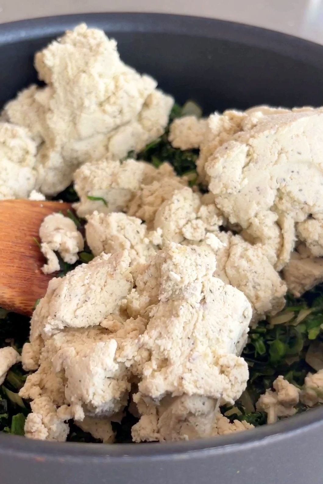 Adding tofu ricotta to spinach mixture.