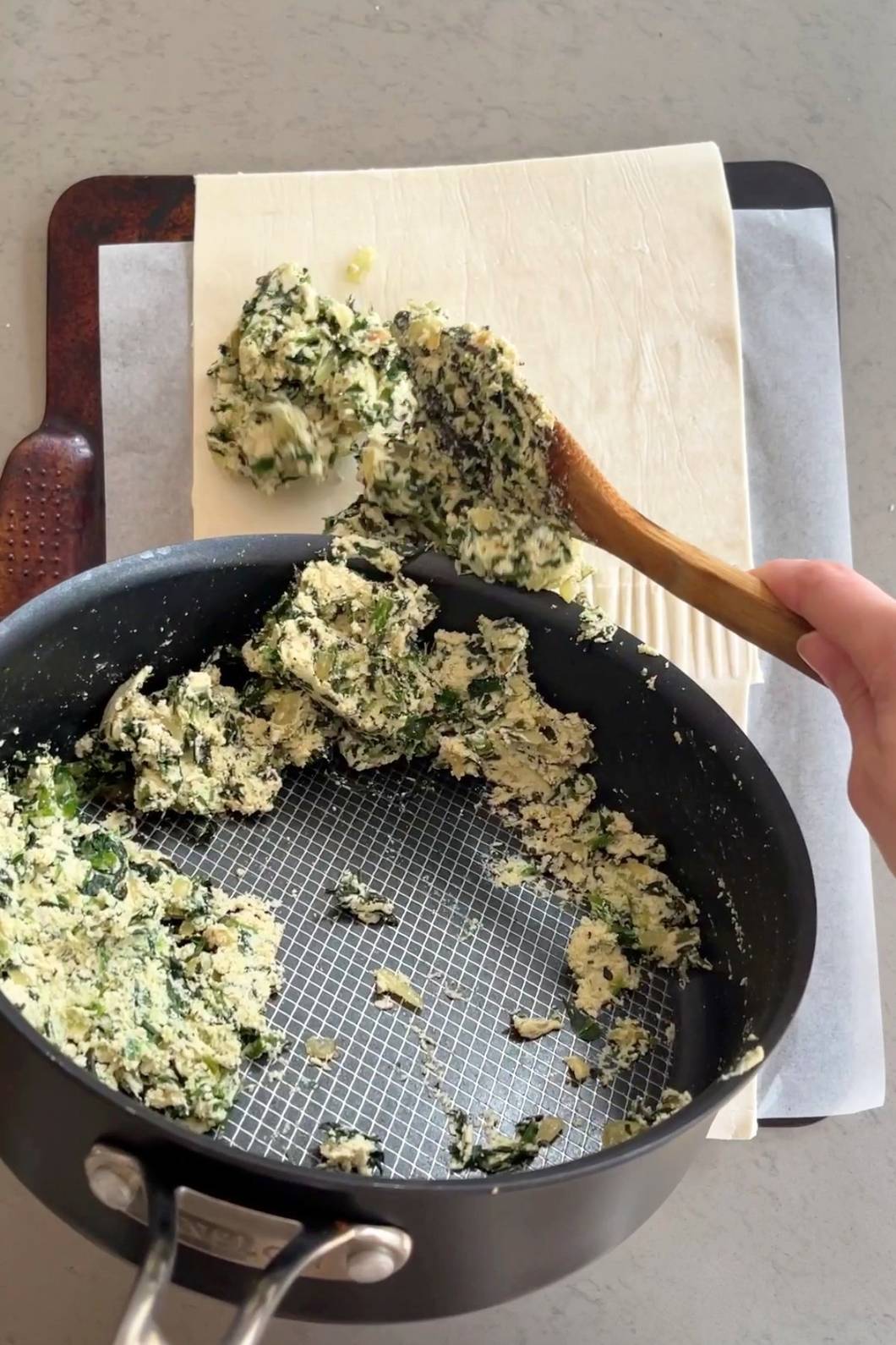 Spooning spinach-tofu filling onto puff pastry.