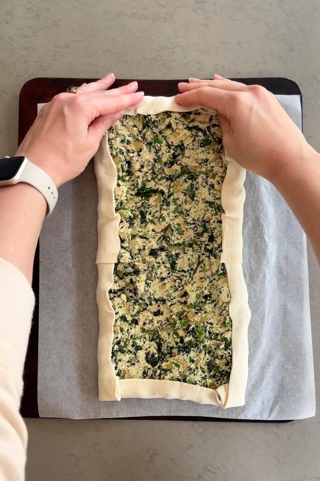 Folding pastry edges over spinach-tofu filling.