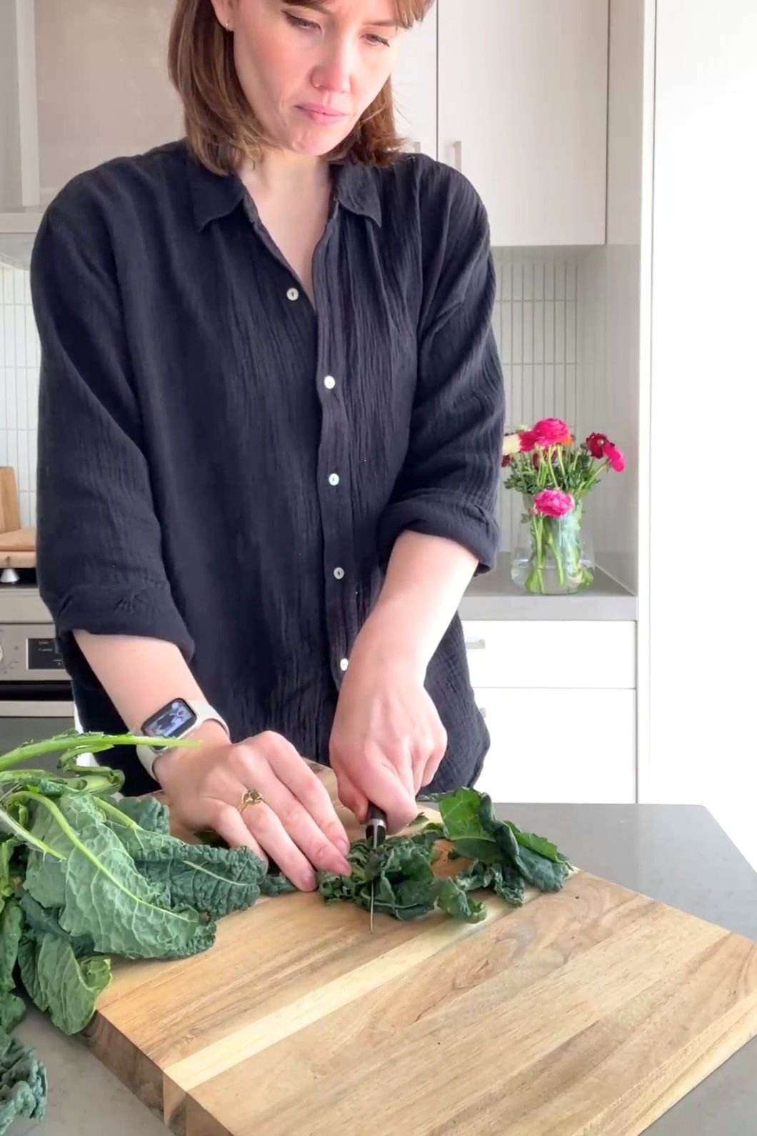Woman (Liz Douglas) chopping kale leaves on a wooden board.