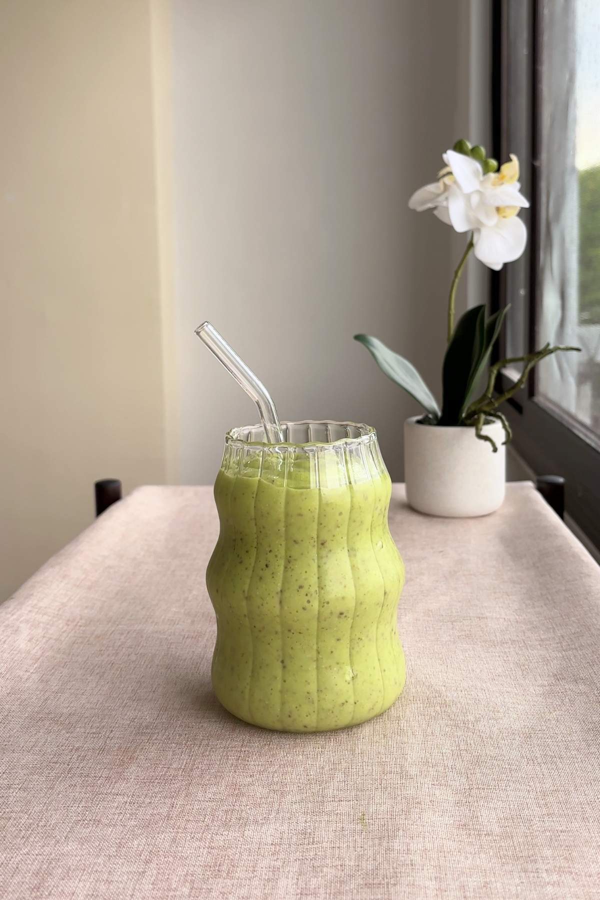 Green smoothie in a textured glass, shown at a slight angle.
