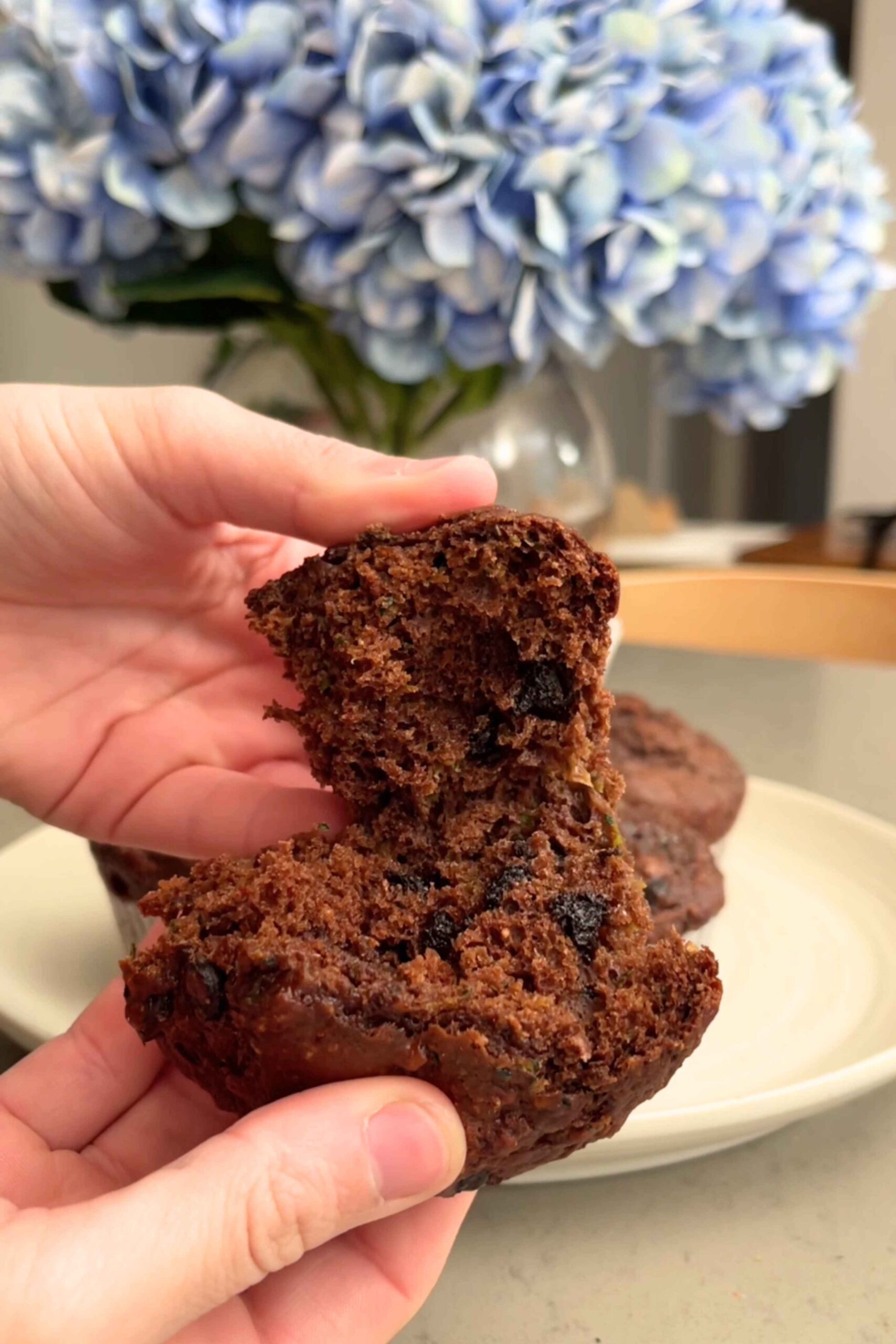 Fingers gently pulling apart a chocolate muffin.