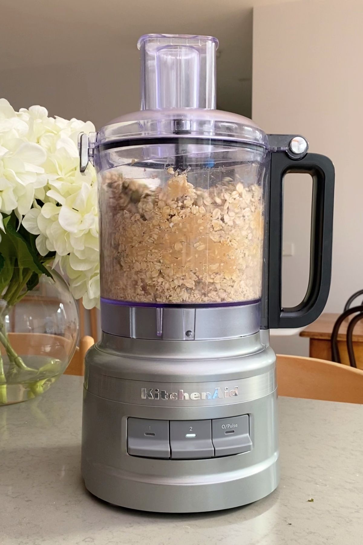 Oats and peanut butter blending into coarse crumbs in a food processor.
