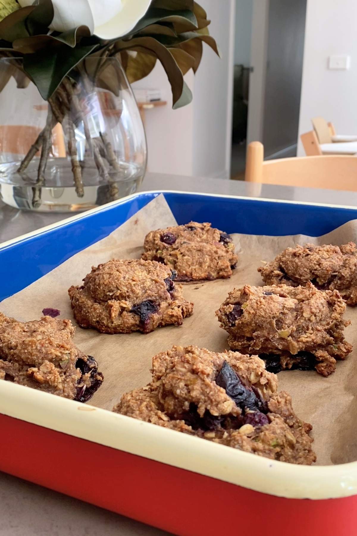 Six golden-brown oat cookie mounds on parchment in a rectangular baking dish.