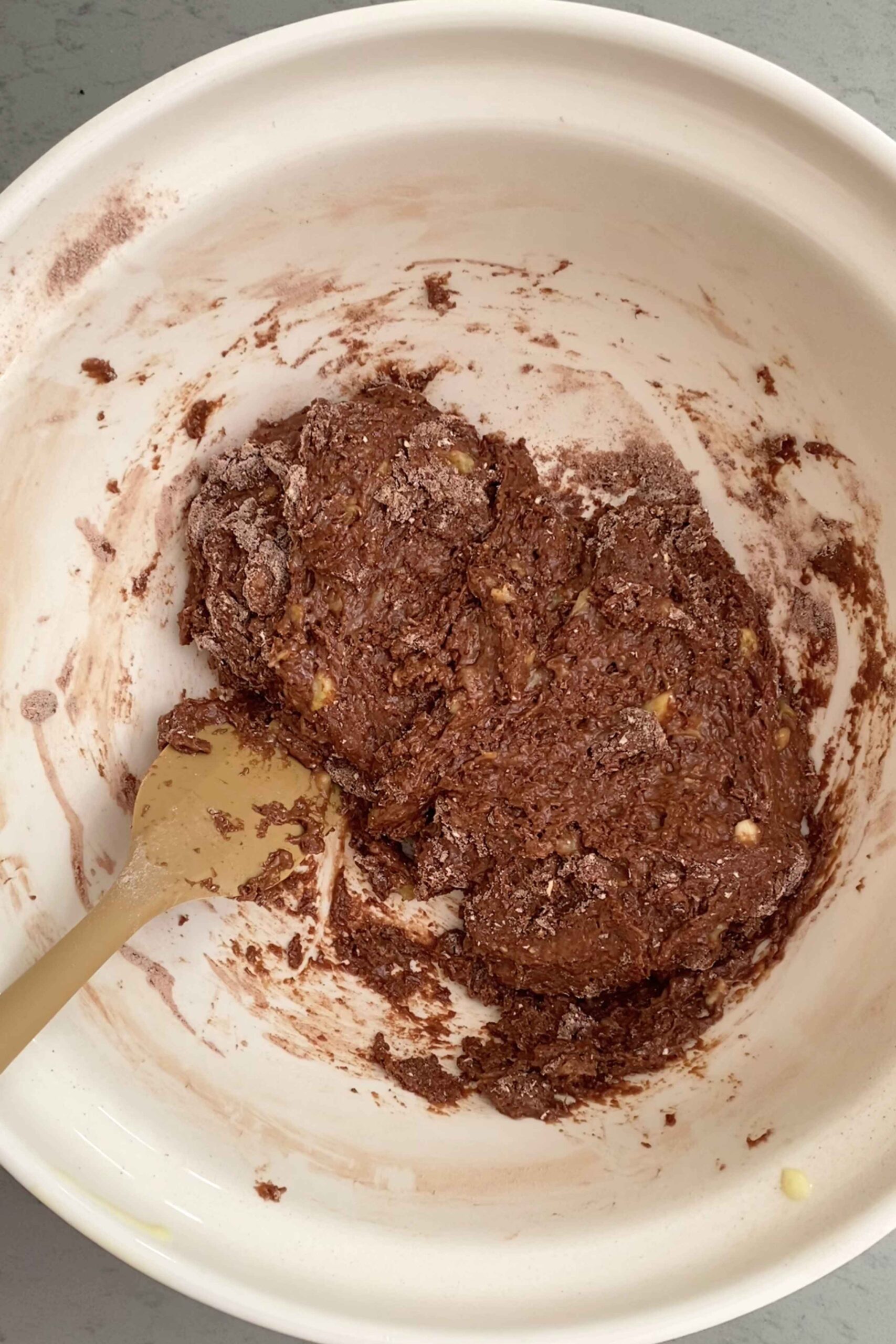 Partially mixed chocolate batter clinging to the sides of a white bowl.