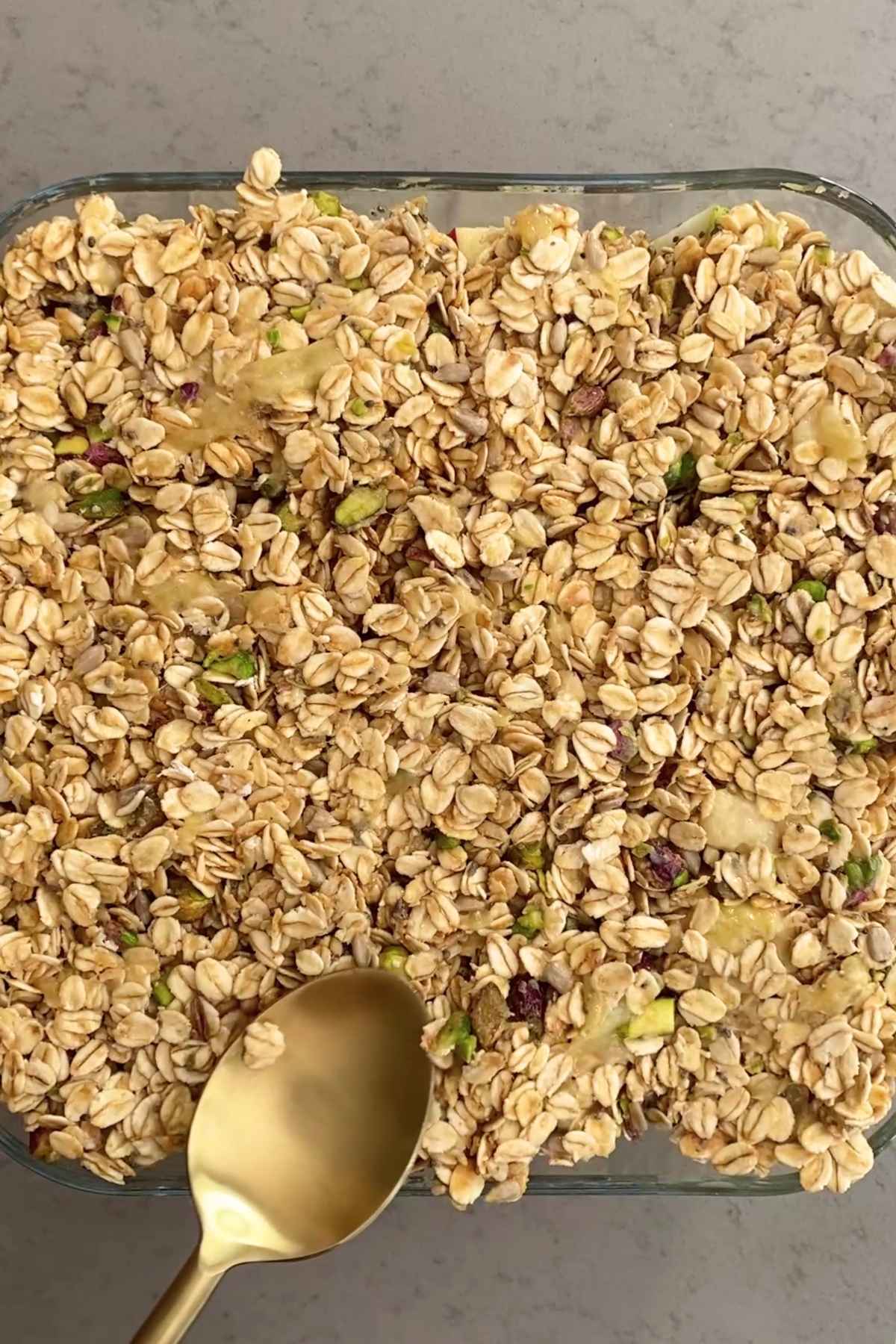 Oat-and-seed topping being spread evenly over the fruit layer.