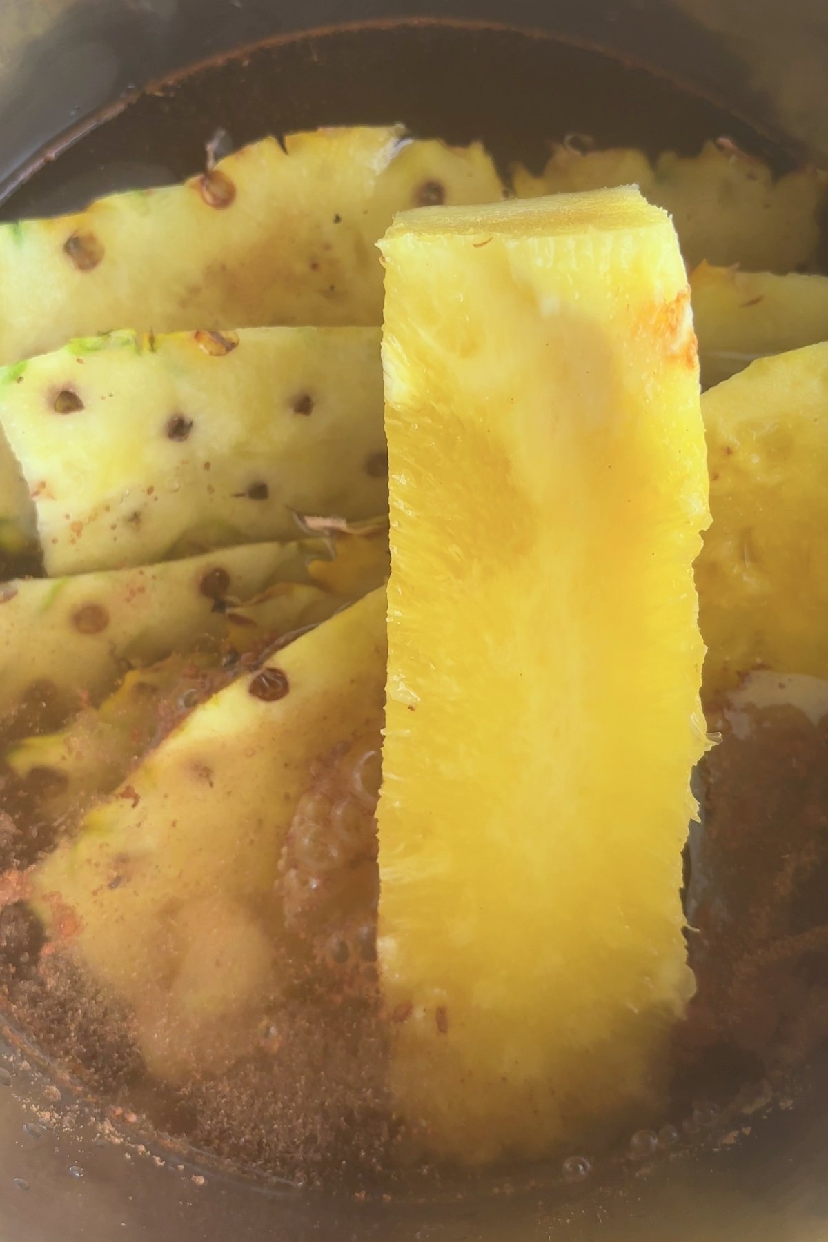 Close-up of a pineapple wedge and skins steeping in bubbling tea.