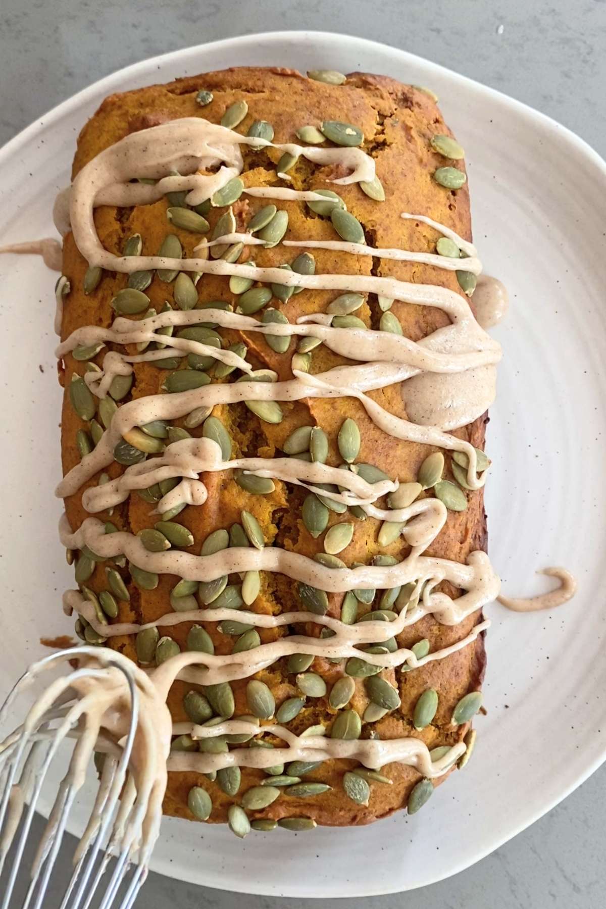 Whisk drizzling creamy glaze in ribbons over a pepita-topped pumpkin loaf.