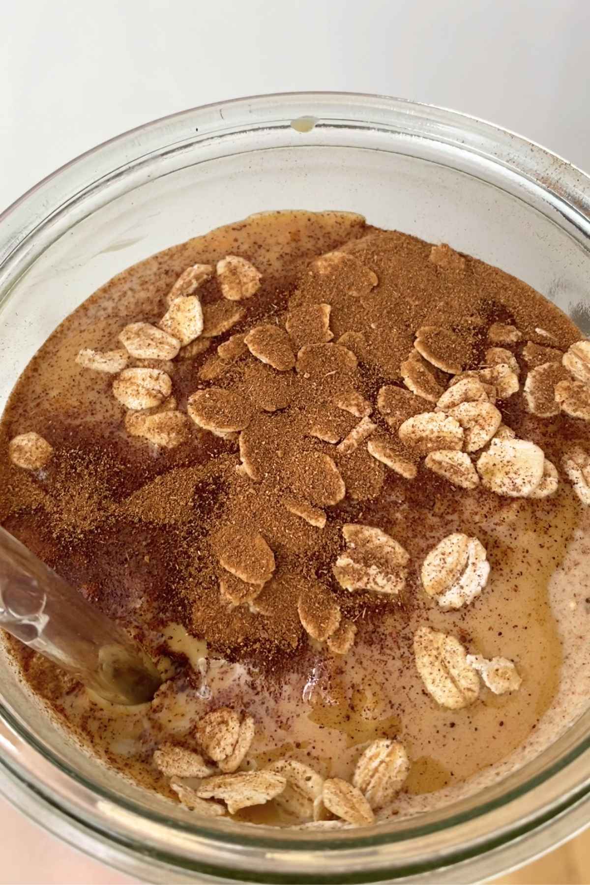 Close-up on smoothie surface sprinkled with oat flakes and cinnamon dusting.