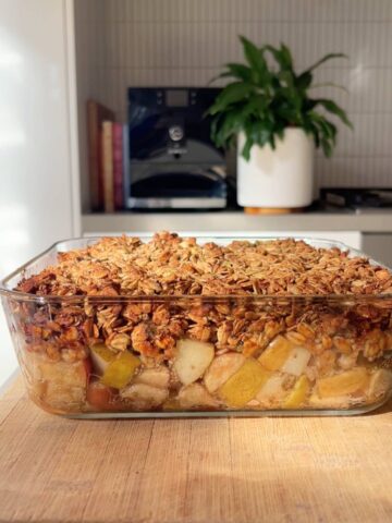 Glass dish filled with golden oat-and-seed topping over bubbling fruit.