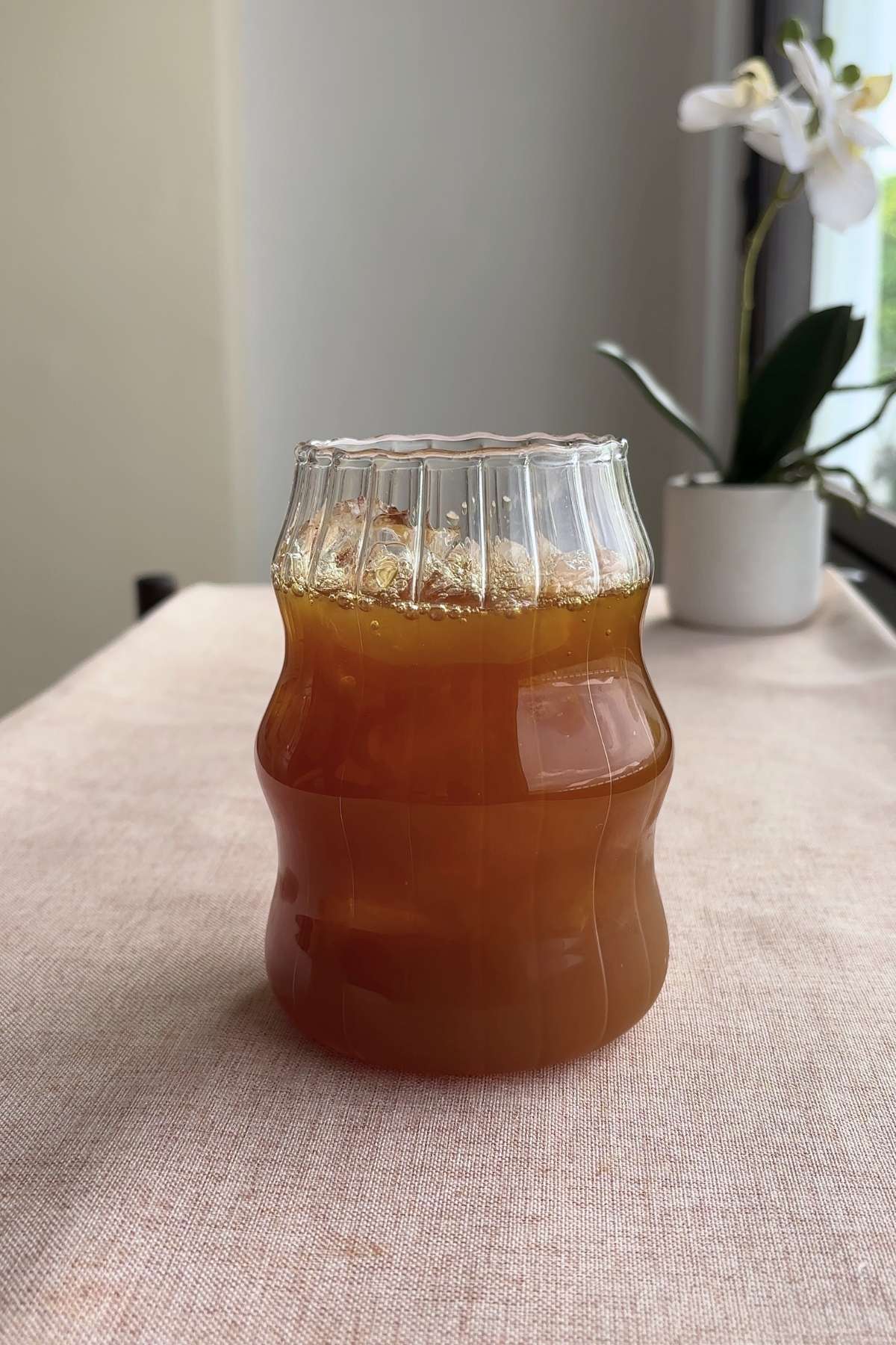 Ribbed glass holding amber tea and ice with a bent glass straw inserted.