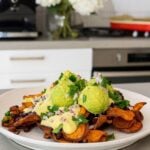 Sweet potato chips topped with creamy sauce, mashed avocado, black beans, red onion, and fresh cilantro.