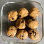 Top view of a glass container holding eight dough balls with chocolate chips.