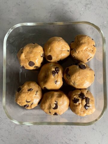 Top view of a glass container holding eight dough balls with chocolate chips.