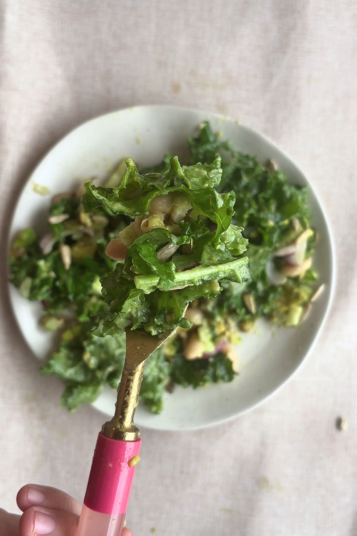 Fork holding kale salad over a plate.