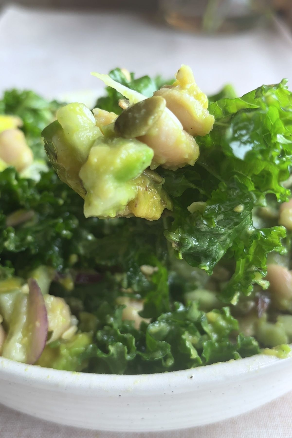 Close-up of kale salad with avocado, beans, and seeds.