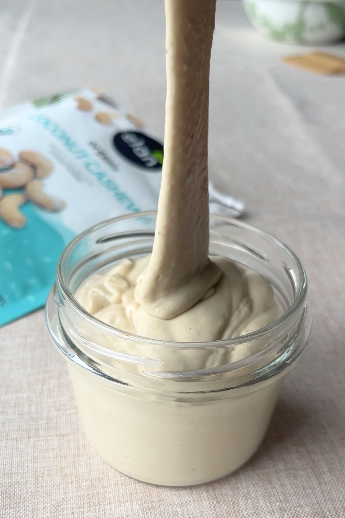 Thick mousse being spooned into a glass jar.
