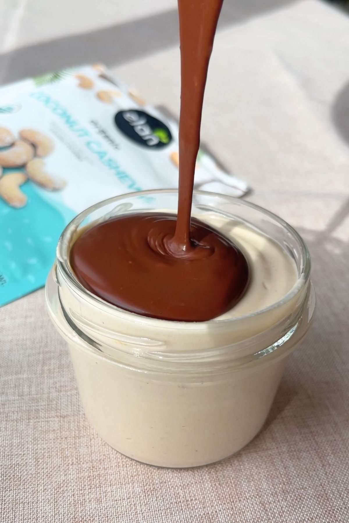 Ganache being poured over set mousse in a jar.
