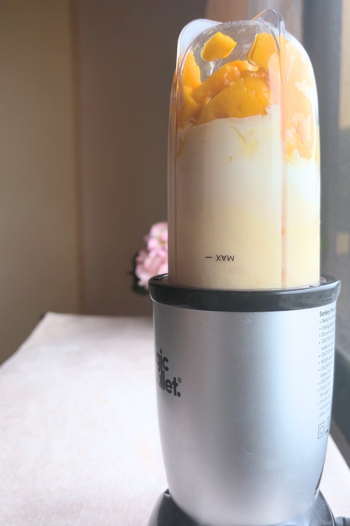Blender cup with mango and yogurt mixture inside a Magic Bullet, ready to blend.