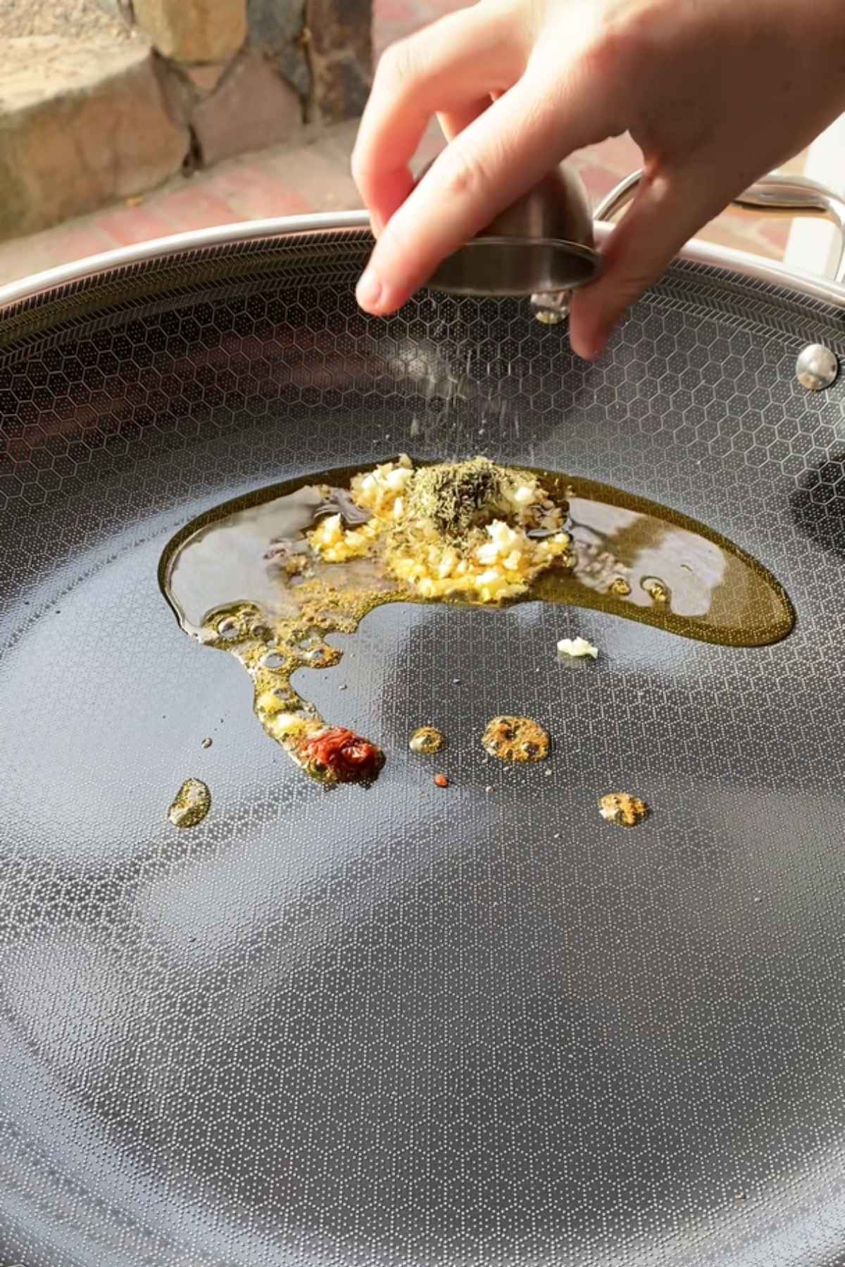 Garlic and herbs sizzling in oil in a skillet.